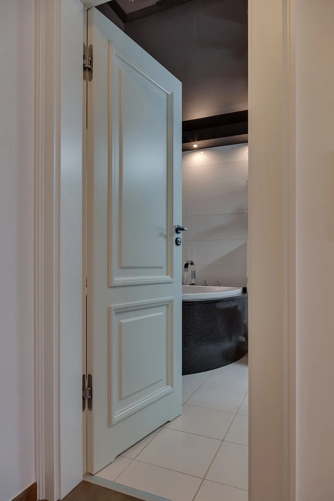 Drzwi do łazienki w kolorze płytek, kontrastujące z ciemnymi elementami wystroju łazienki. 