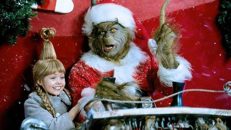 Główny bohater siedzi w stroju Św. Mikołaja w czerwonych saniach wraz z małą dziewczynką – drugą bohaterką filmu.