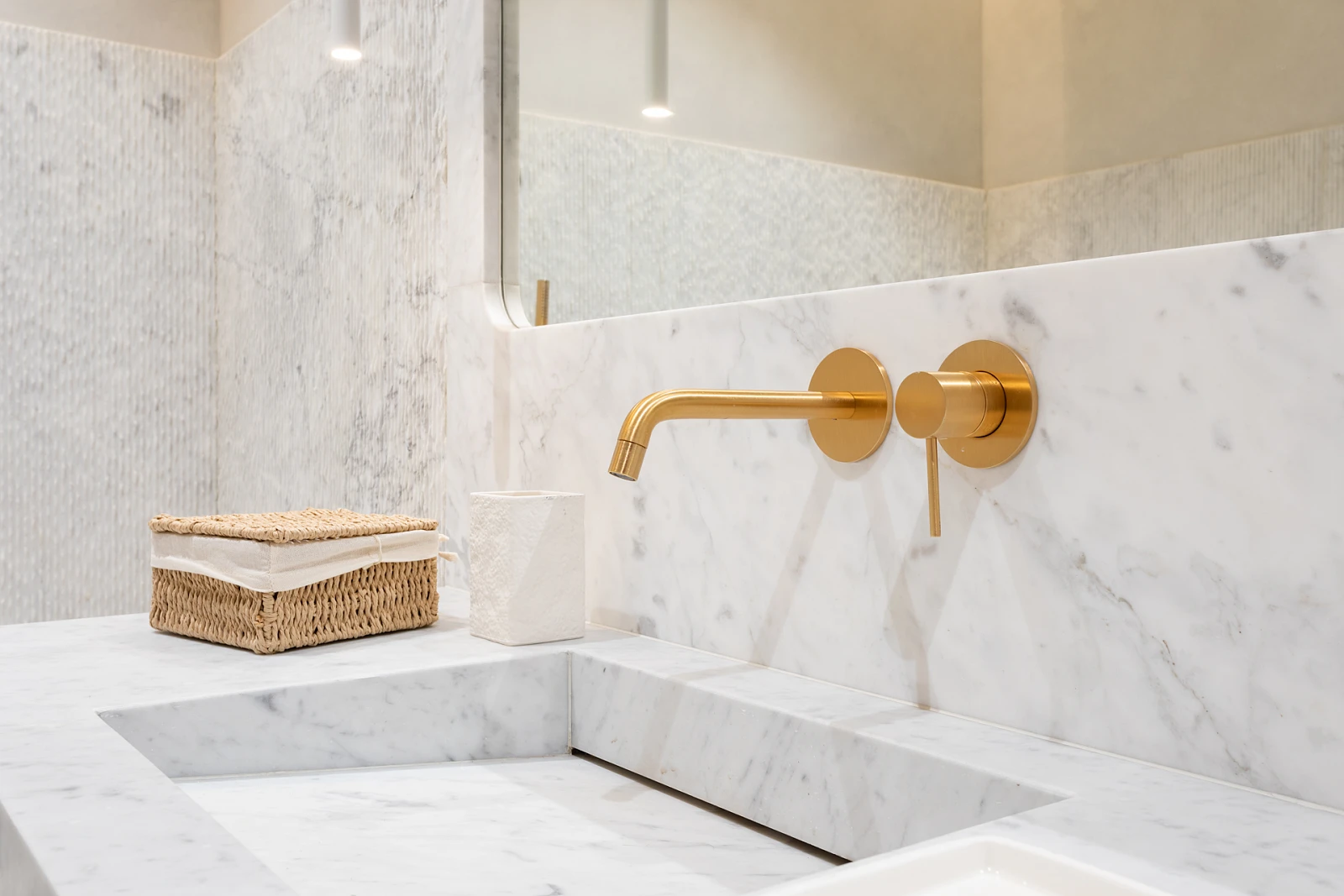 Biała łazienka z kamiennym wykończeniem i złotymi akcentami.