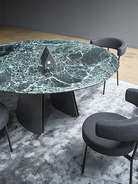 Pomieszczenie z okrągłym stołem o marmurowej fakturze i ciemno-zielonej barwie.