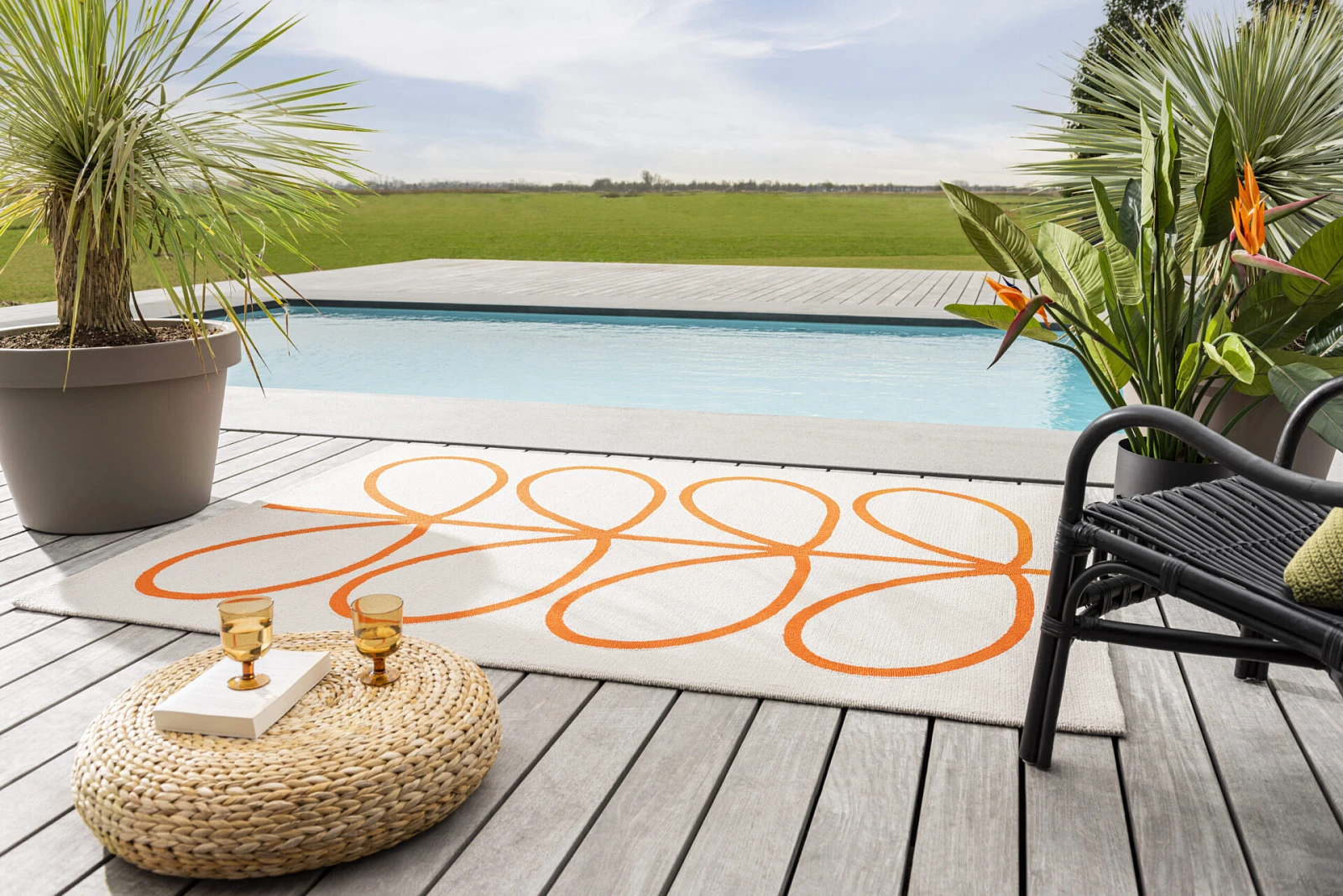 Dywan w kolorze kremowym z pomarańczowym wzorem na tarasie z basenem.